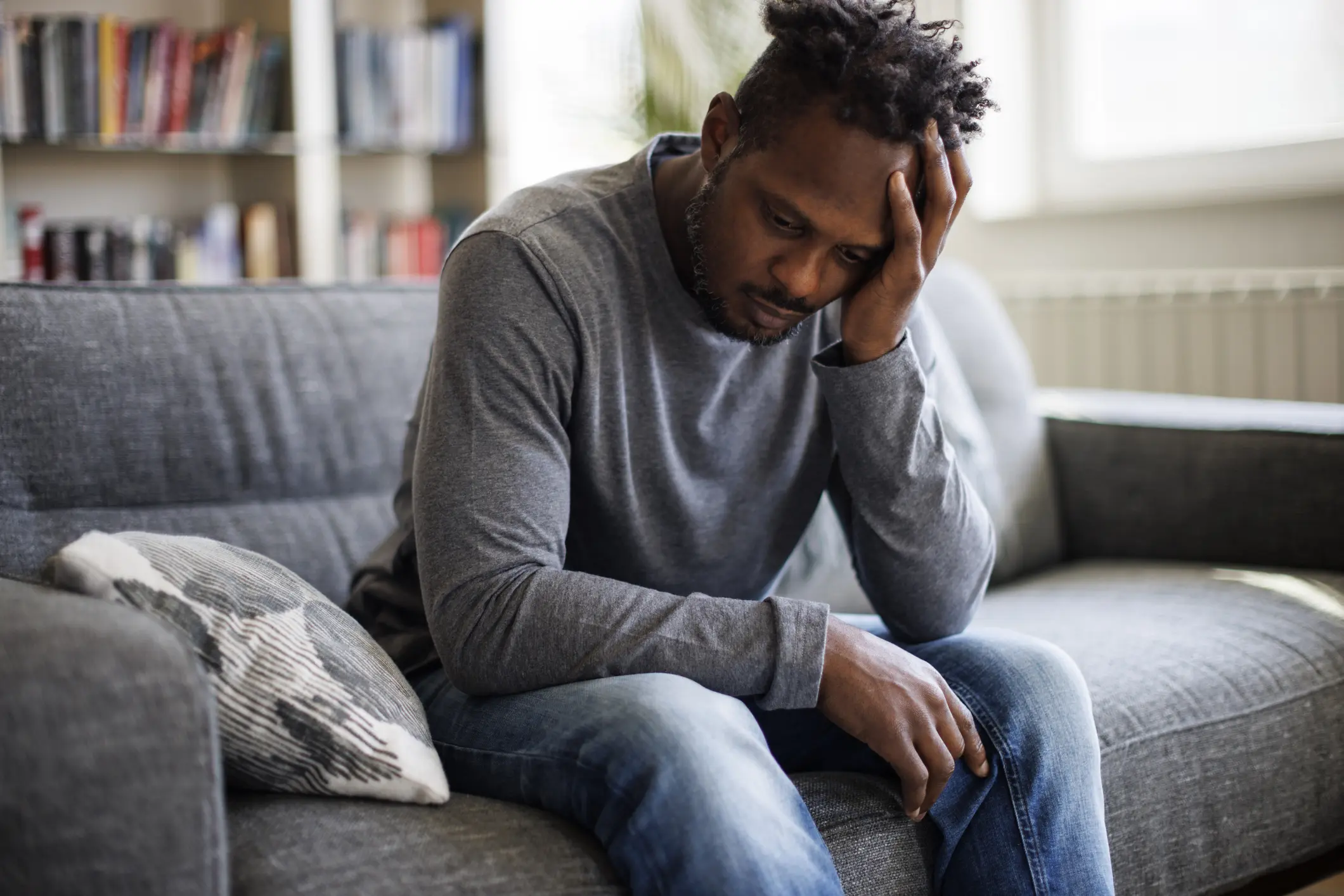 African American man holds his head and struggles with his mental health